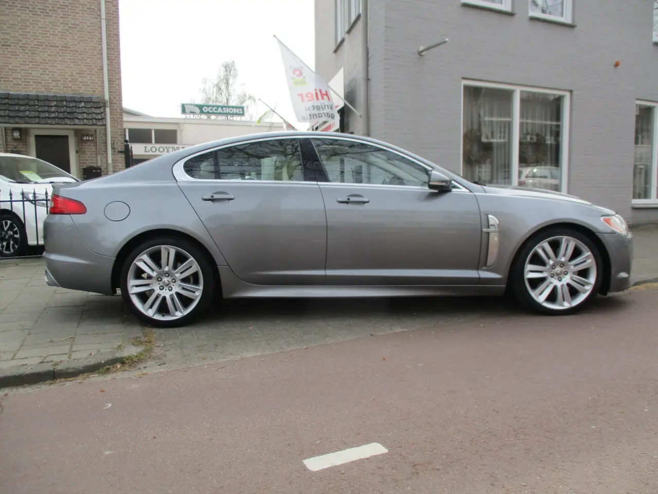 Grijze Jaguar XF van opzij, geparkeerd voor de showroom aan de Helvoirtseweg